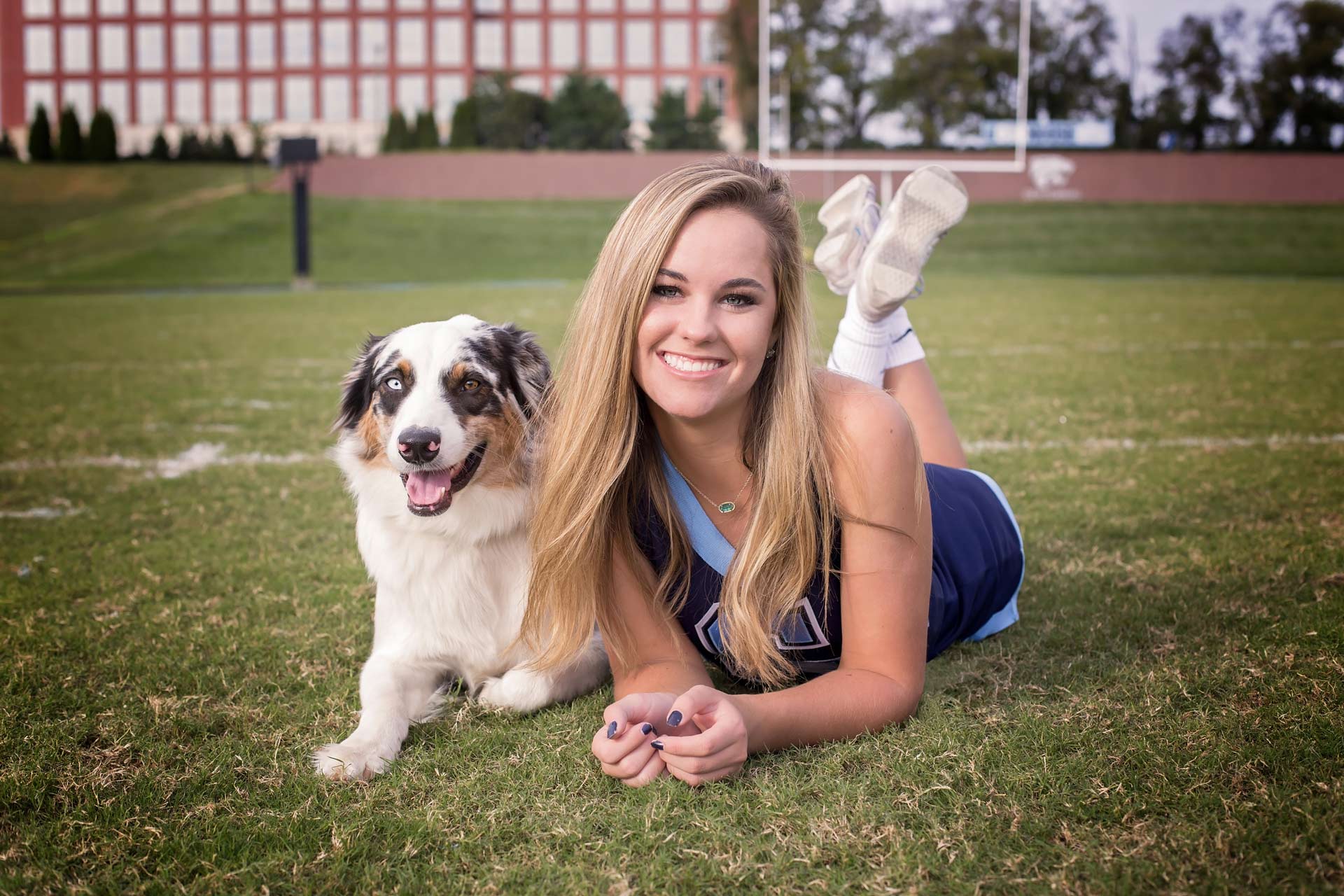 High School Senior Cheerleader Laying with Dog on the grass during a professional senior photography session at Moments By T, Franklin Tennessee
