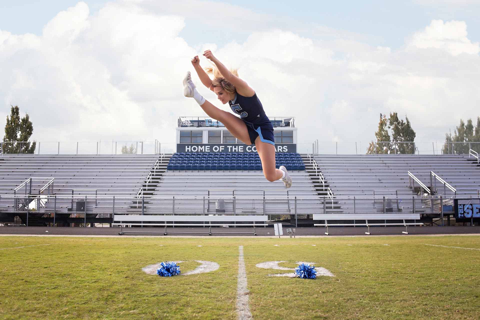 High school senior girl doing a high jump cheerleading pose during a professional senior photography session at Moments By T, Franklin Tennessee
