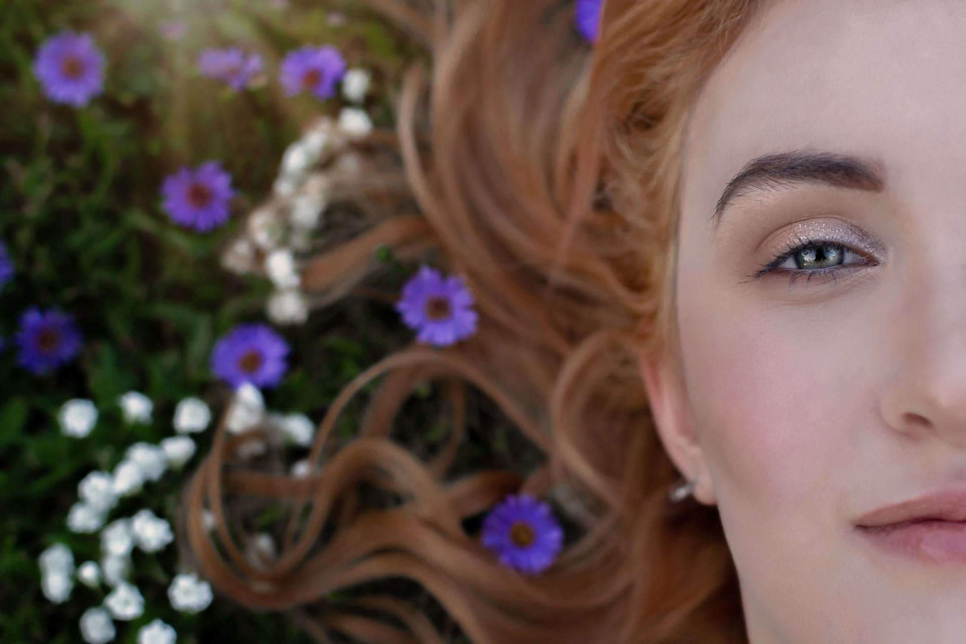 Closeup of redhead teen girl laying down with flowers around her hair during a professional senior photography session at Moments By T, Franklin Tennessee