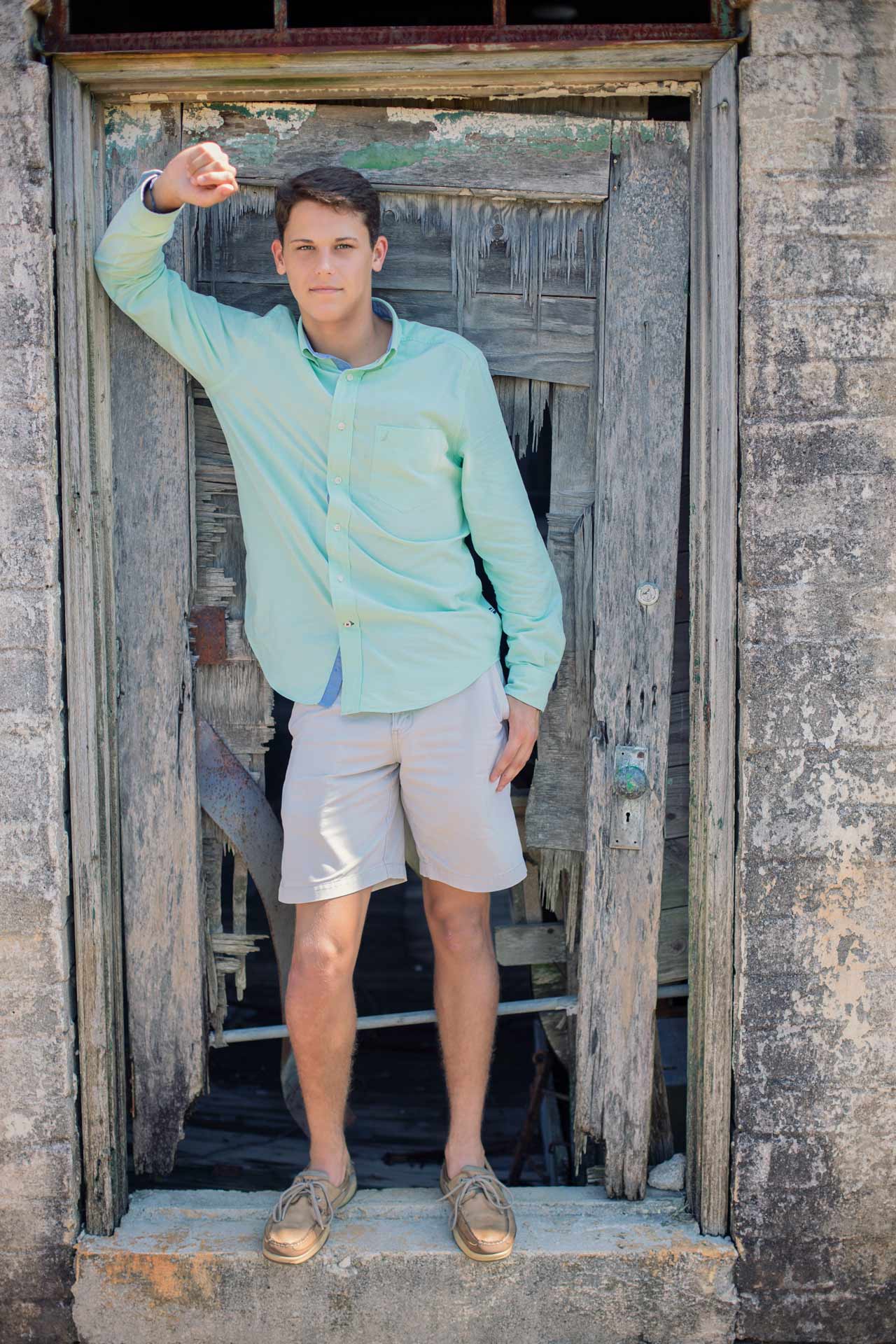senior boy standing in a barn doorway during a professional high school photography by leading photographer Moments By T