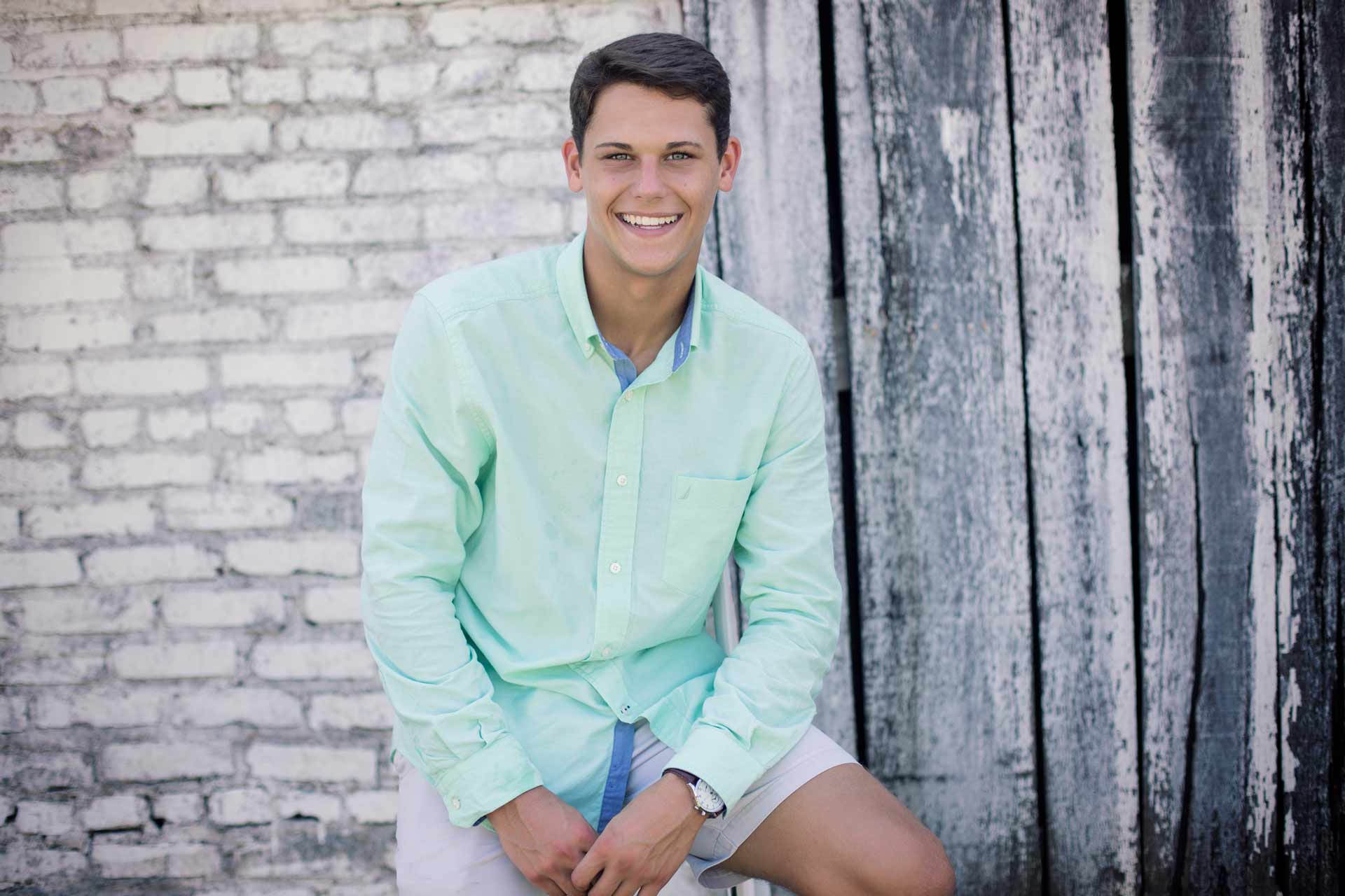 senior boy sitting with his hands on his lap during a professional senior photography session at Moments By T, Franklin Tennessee