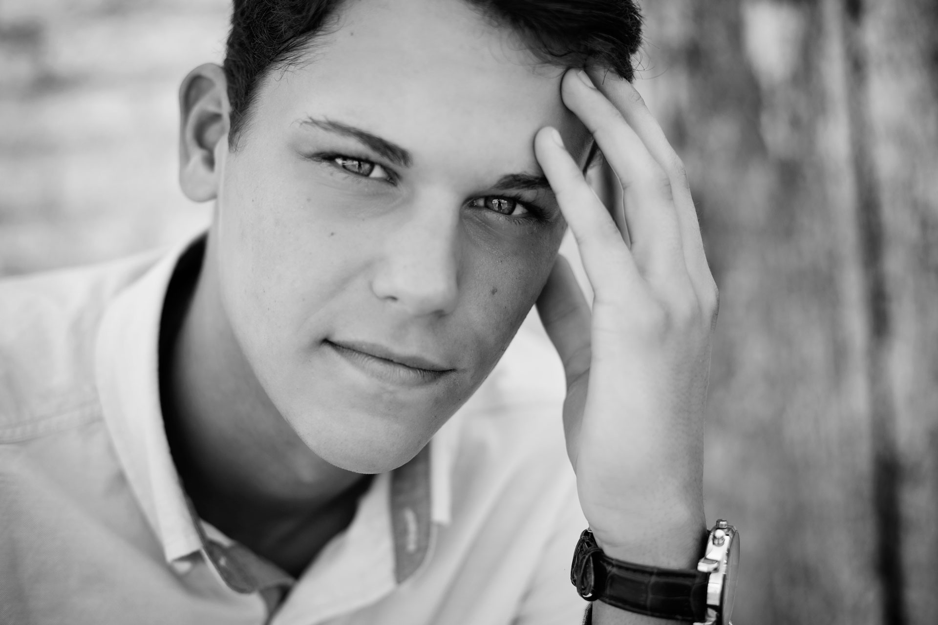 senior boy sitting with his fingers touching his forehead during a professional senior photography session at Moments By T, Franklin Tennessee